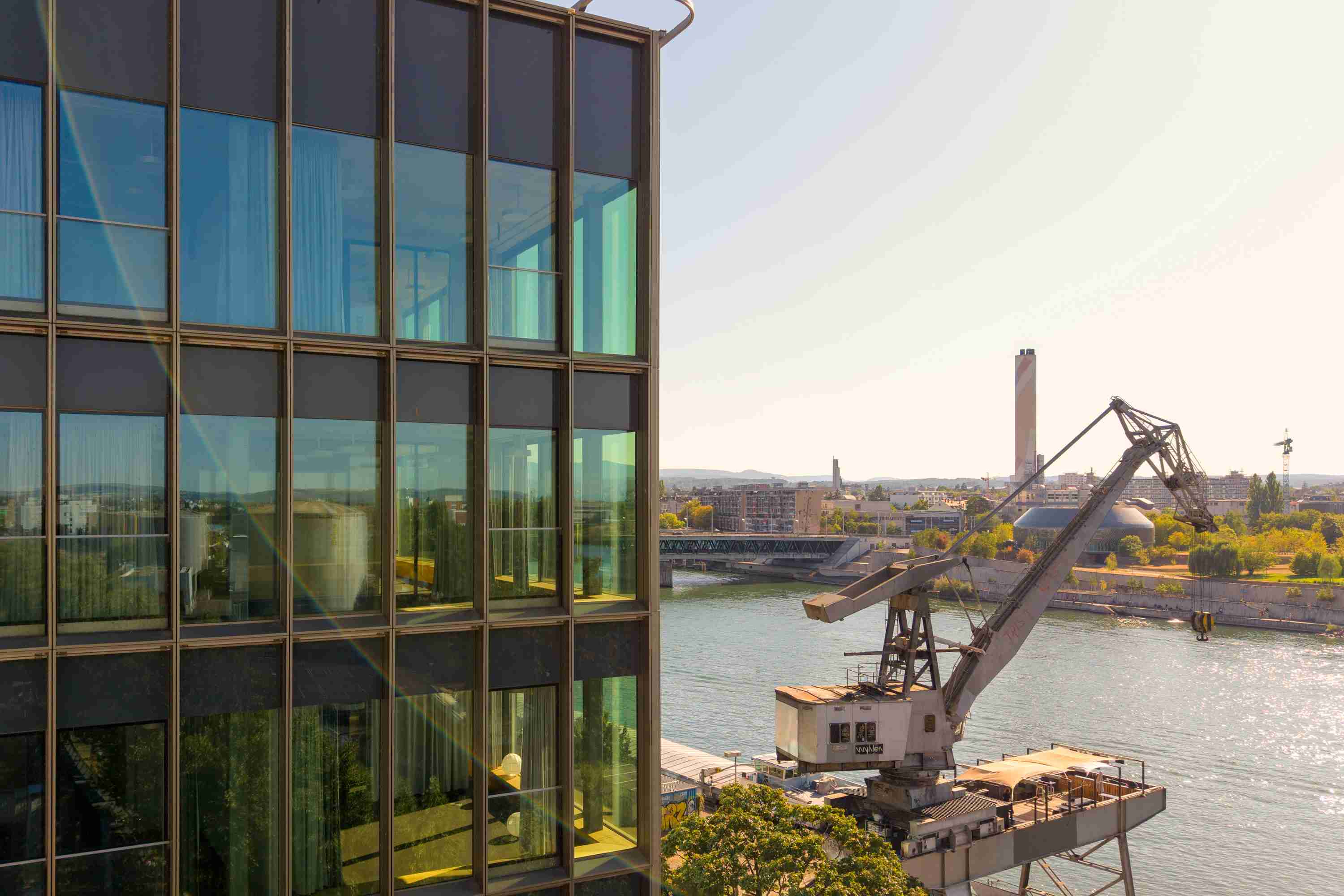 View of the building WKL-132 on the Klybeck site in Basel with the River Rhine and the center of Basel in the background and a crane visible on the right of the building.