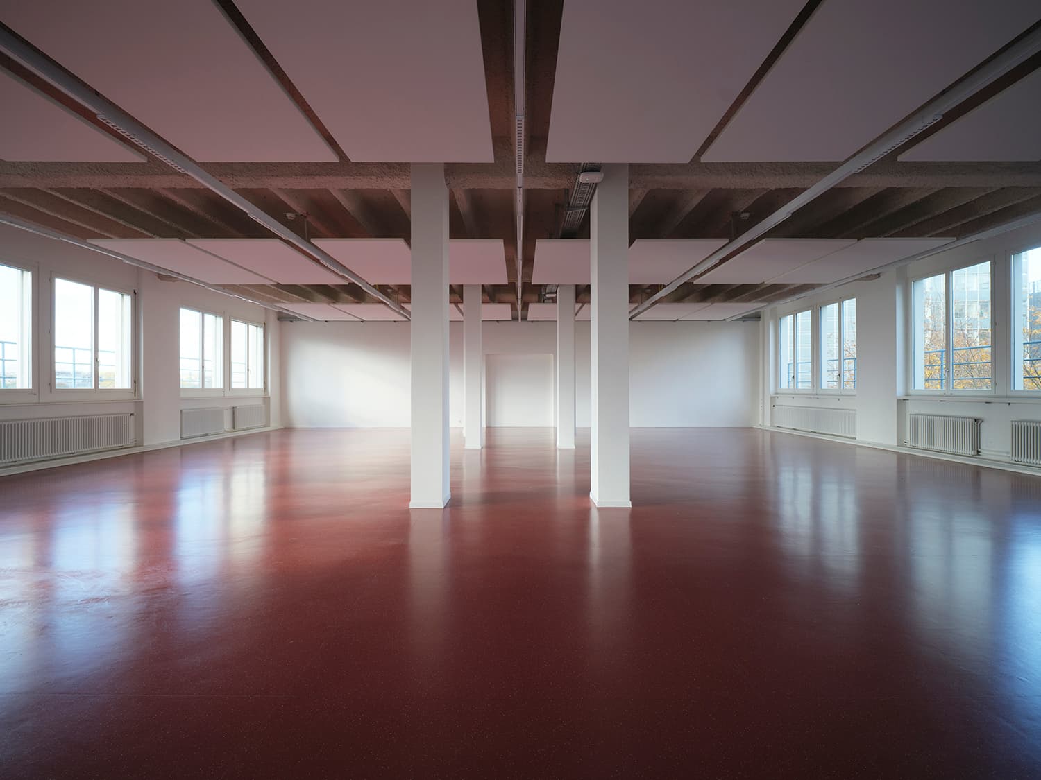 Innenansicht vom Gebäude WKL-121 im Neuen Klybeck in Basel mit einem grossen Raum mit rotem Boden und weissen Tragsäulen
