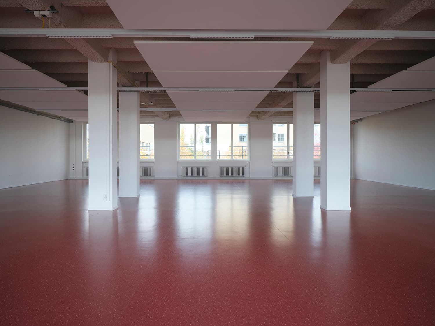 Innenansicht vom Gebäude WKL-121 im Neuen Klybeck in Basel mit einem grossen Raum mit rotem Boden und weissen Tragsäulen