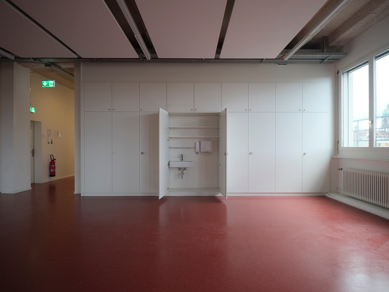 Innenansicht vom Gebäude WKL-121 im Neuen Klybeck in Basel mit einem grossen Raum mit rotem Boden und Einbauschränken