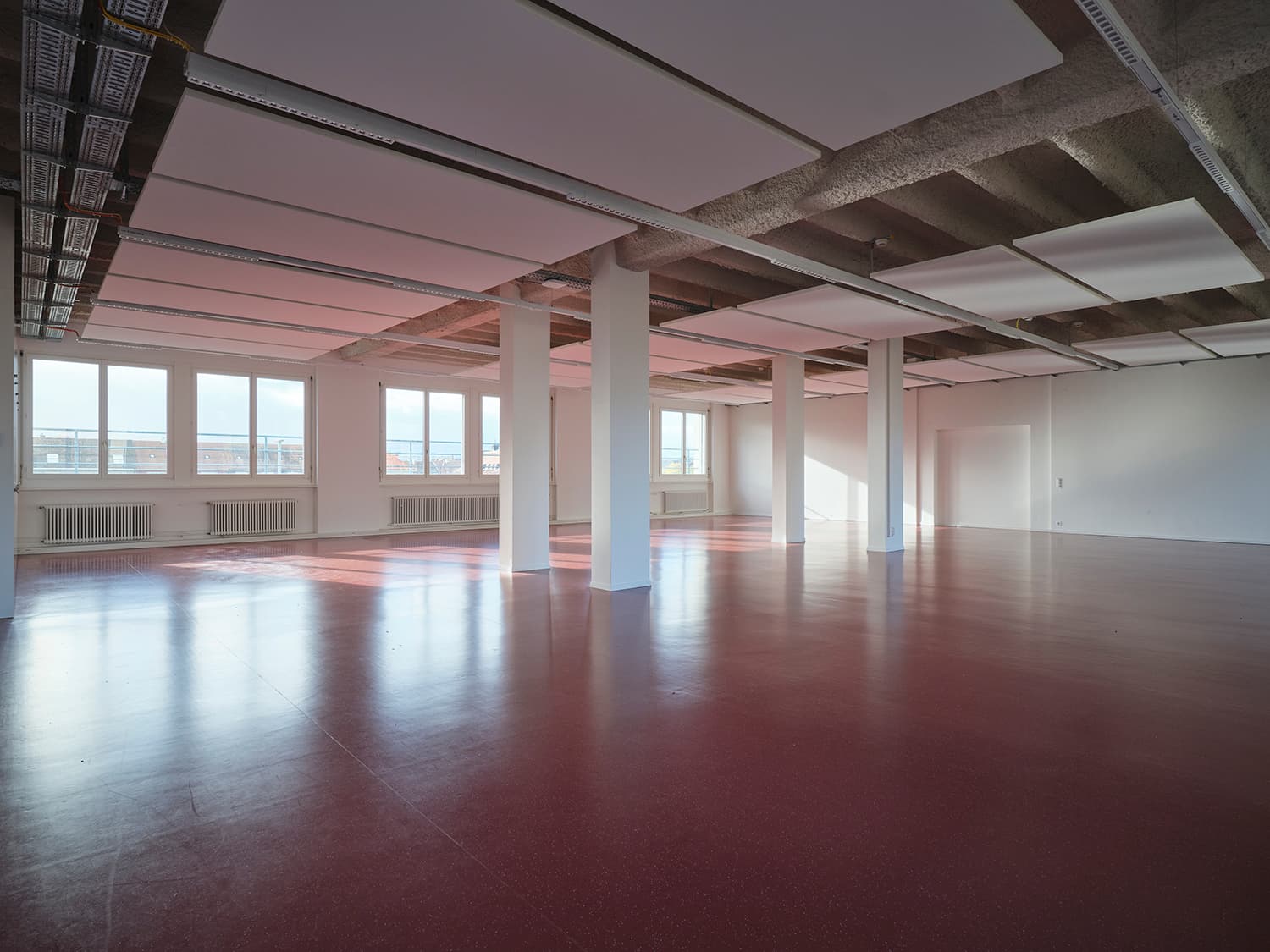 Innenansicht vom Gebäude WKL-121 im Neuen Klybeck in Basel mit einem grossen Raum mit rotem Boden und weissen Tragsäulen