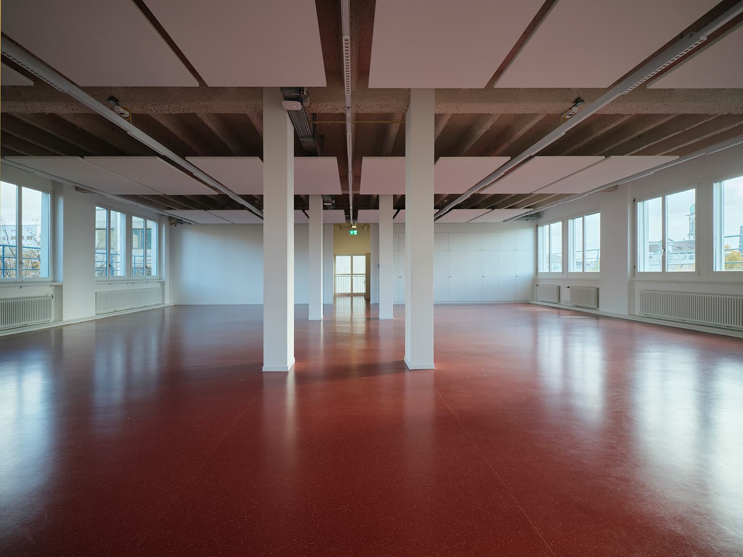 Innenansicht vom Gebäude WKL-121 im Neuen Klybeck in Basel mit einem grossen Raum mit rotem Boden und weissen Tragsäulen