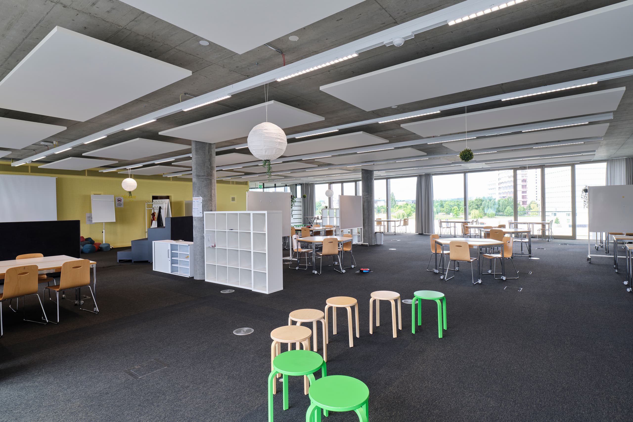 View of a large multifunctional room in the building WKL-132 in the Klybeck site in Basel with large windows and textile floors and chairs