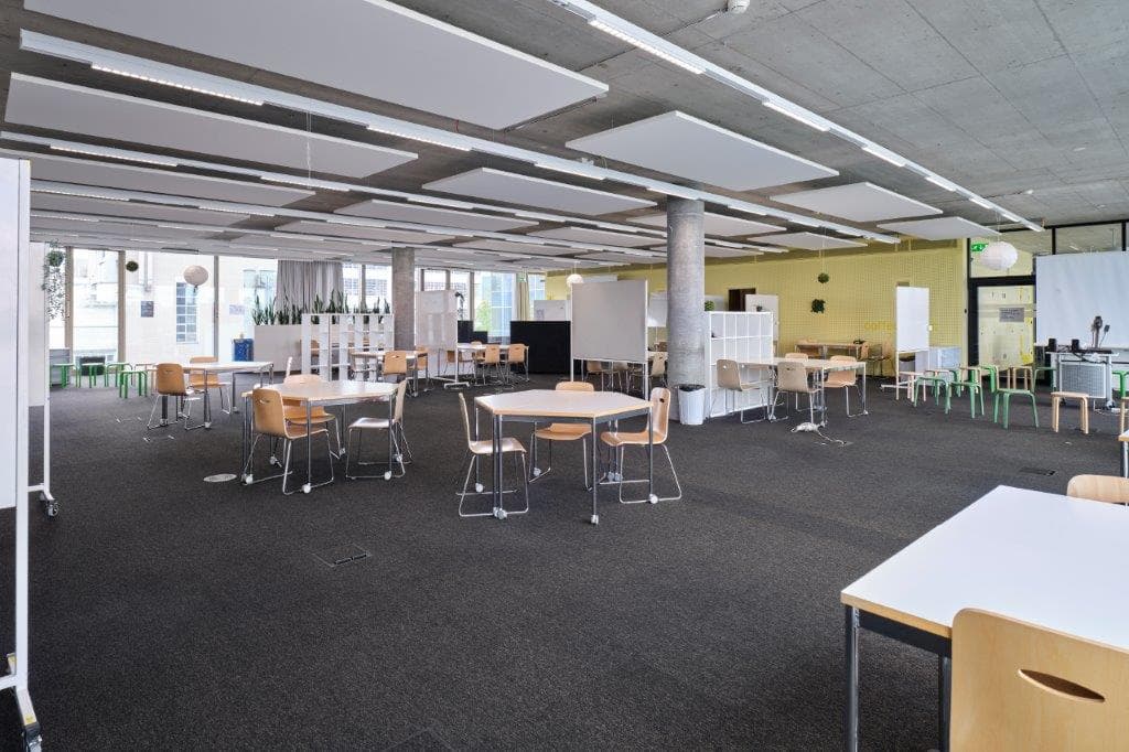 View of a large multifunctional room in the building WKL-132 in the Klybeck site in Basel with textile floors and several tables spread out