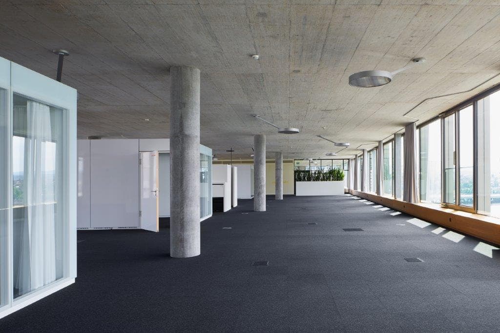 Internal view of a large multifunctional room in the building WKL-132 on the Klybeck site in Basel with concrete pillars and textile floors