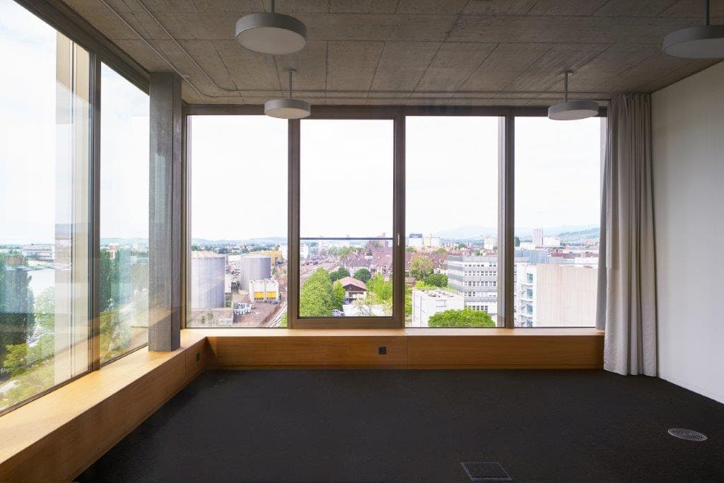 View of a corner room in the building WKL-132 on the Klybeck site in Basel with large windows on the surroundings and textile floors