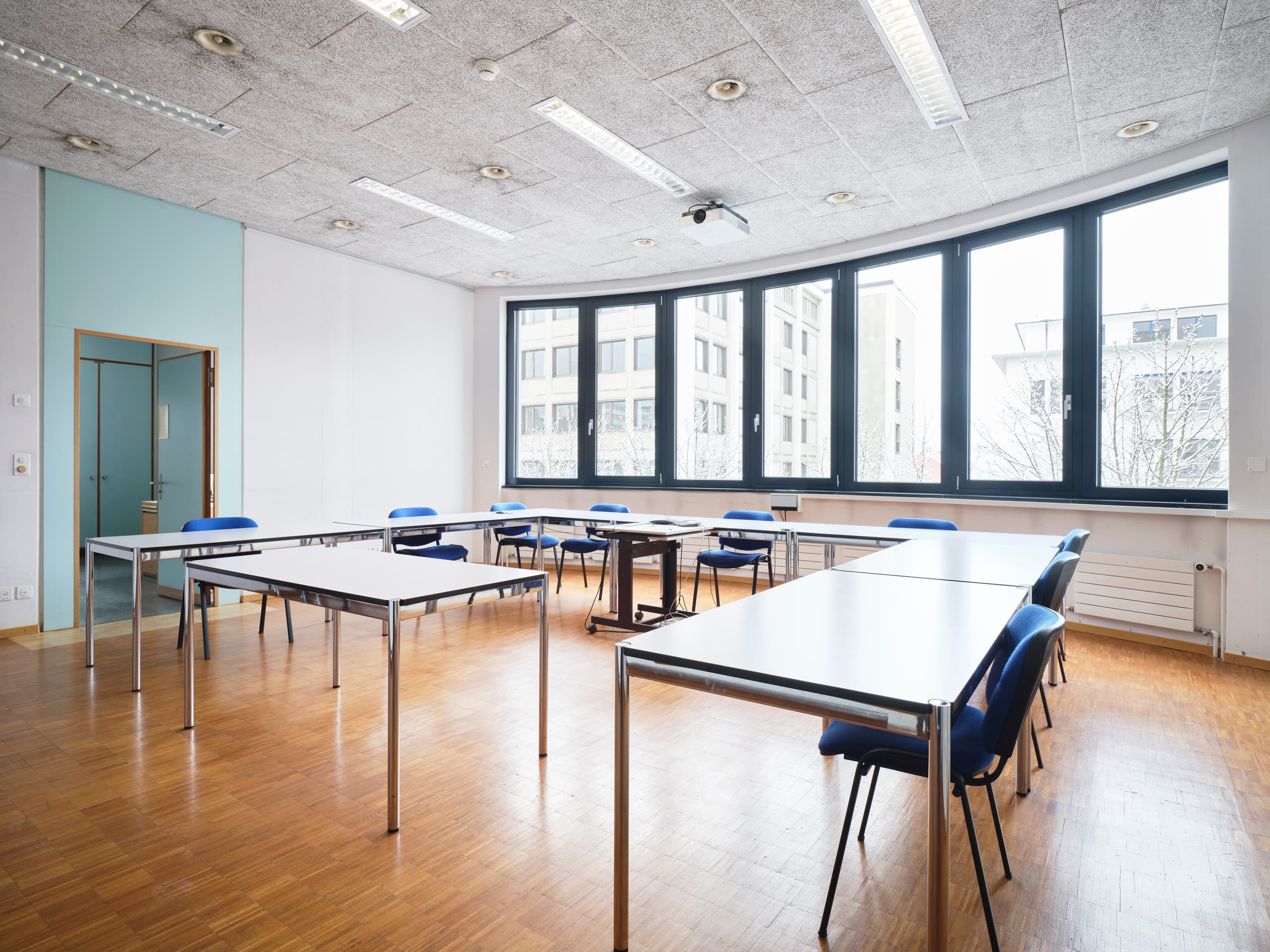 View of a meeting room in the building WKL-136 in the Klybeck site in Basel showing desks and chairs and a large curved window in the middle of the picture