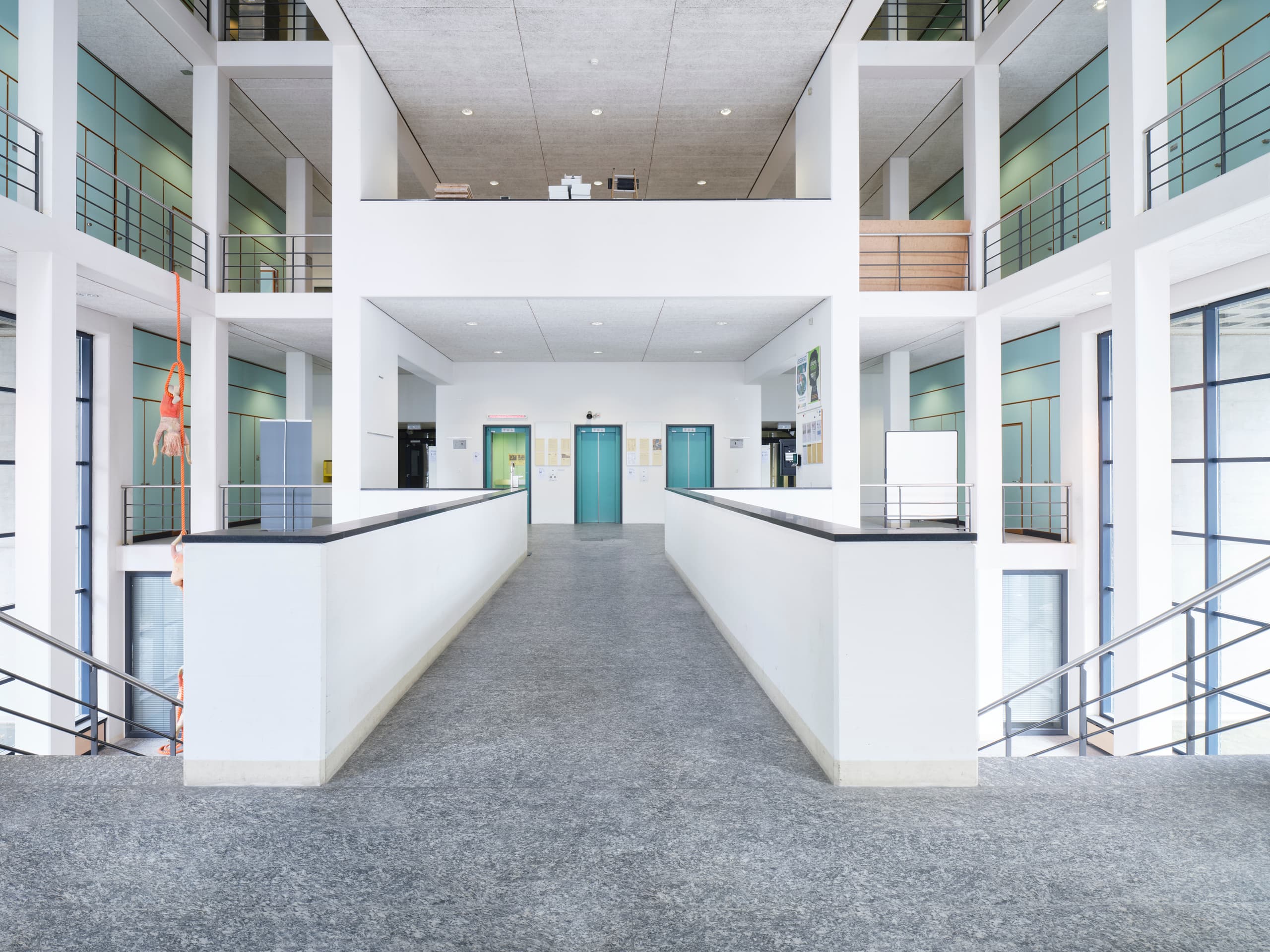 View of the spacious lobby of the building WKL-136 in the Klybeck site in Basel showing a corridor with a grey floor leading to the lift doors as well as stairs on the left and the right side of the picture