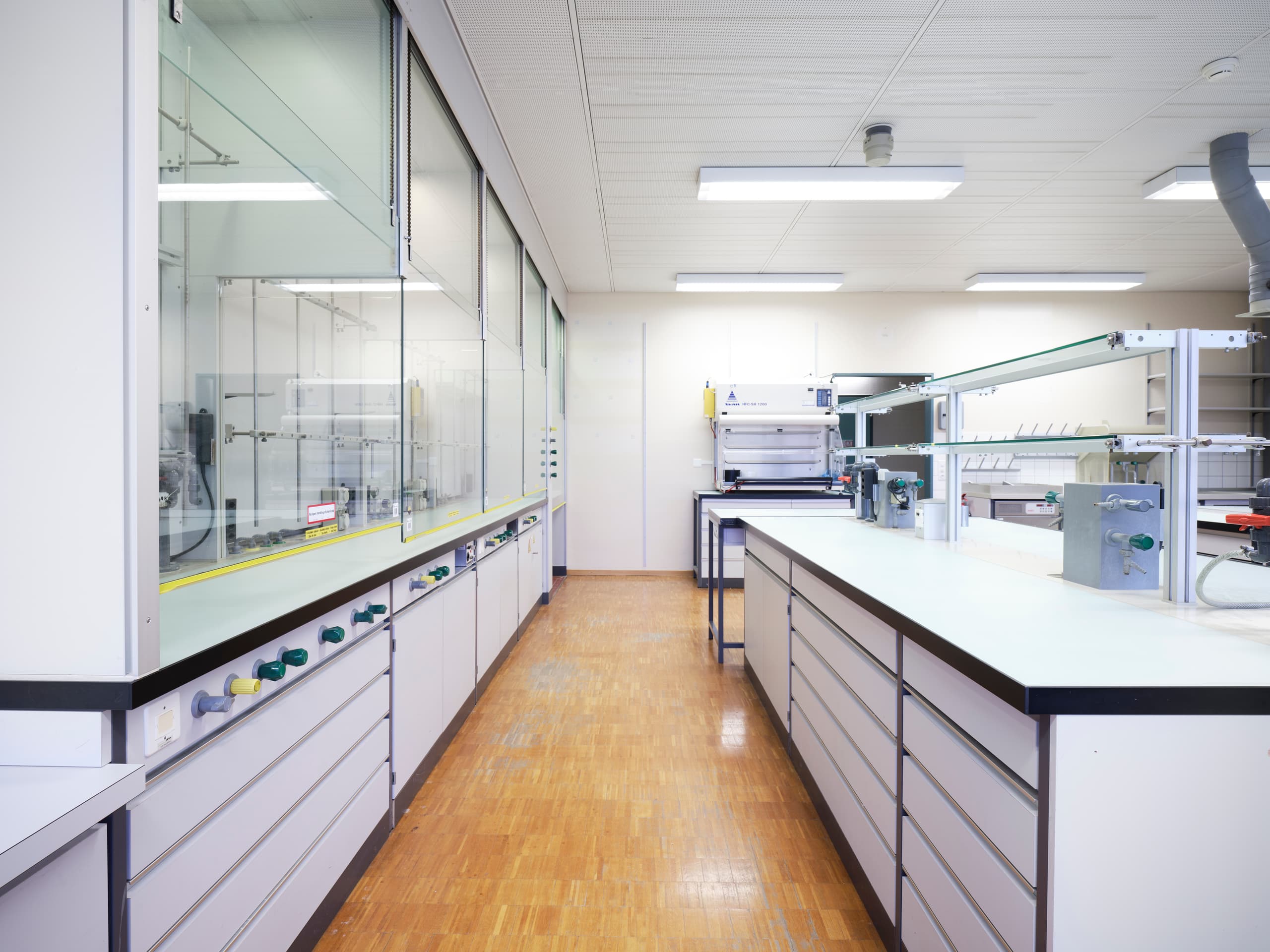 View of a labarotary in the building WKL-136 in the Klybeck site in Basel with glass-portectes shelves and drawers on the left as well as a working area and drawers on the right